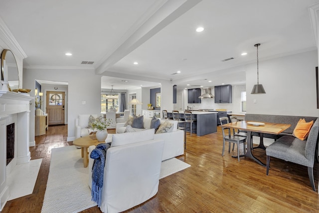 living room featuring a fireplace, plenty of natural light, ornamental molding, and light hardwood / wood-style flooring