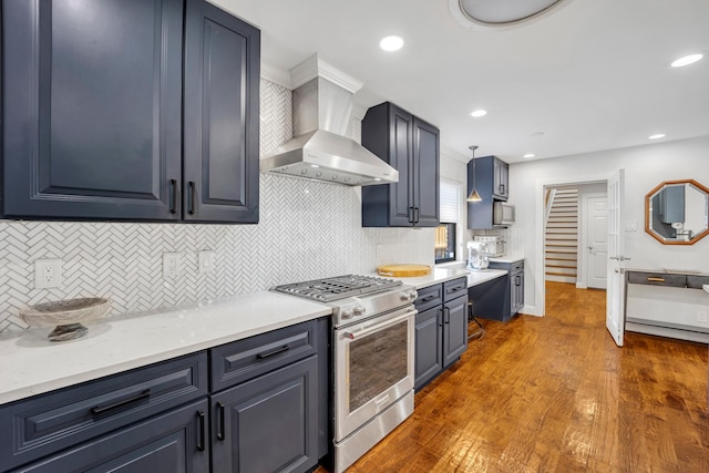 kitchen with gas stove, dark hardwood / wood-style floors, decorative light fixtures, wall chimney exhaust hood, and light stone countertops