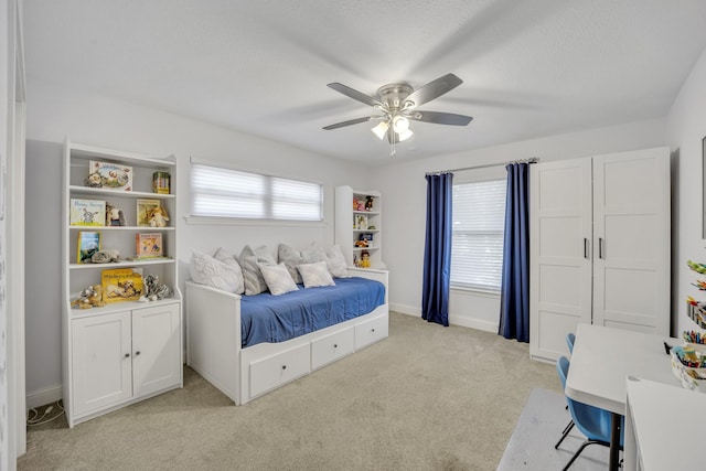 bedroom with a textured ceiling, ceiling fan, and light colored carpet