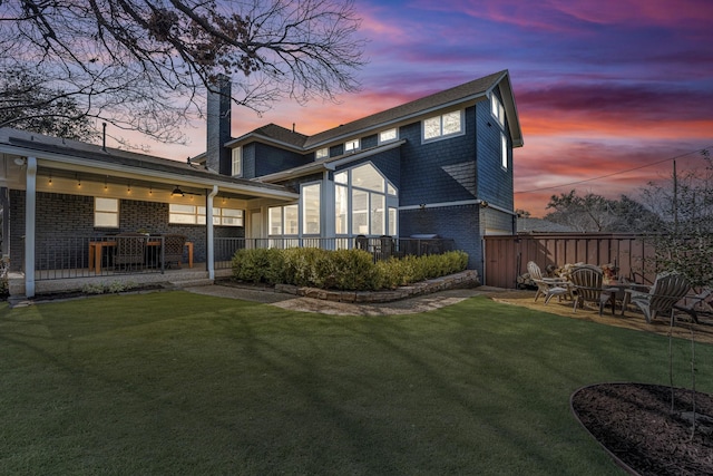 back house at dusk with a lawn