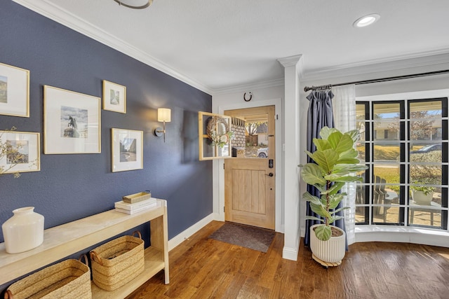 foyer featuring decorative columns, ornamental molding, and hardwood / wood-style flooring