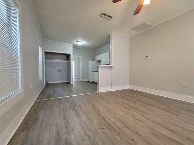 unfurnished living room featuring ceiling fan, light hardwood / wood-style flooring, crown molding, and a textured ceiling