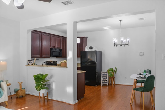 kitchen with dark hardwood / wood-style flooring, decorative light fixtures, black appliances, ceiling fan, and light stone counters