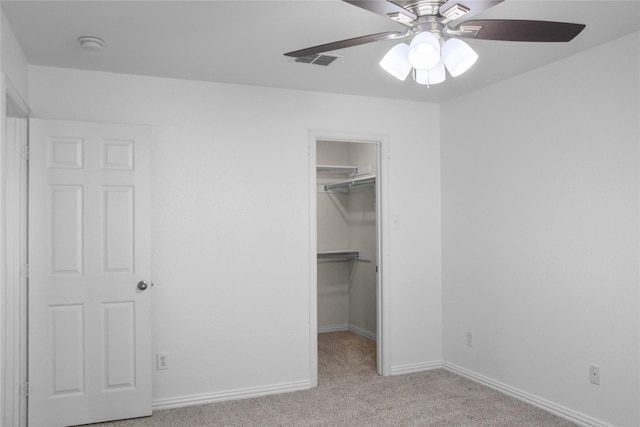 unfurnished bedroom featuring ceiling fan, a closet, light colored carpet, and a spacious closet