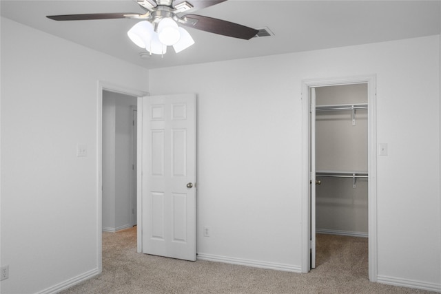 unfurnished bedroom with light carpet, a walk in closet, and a closet