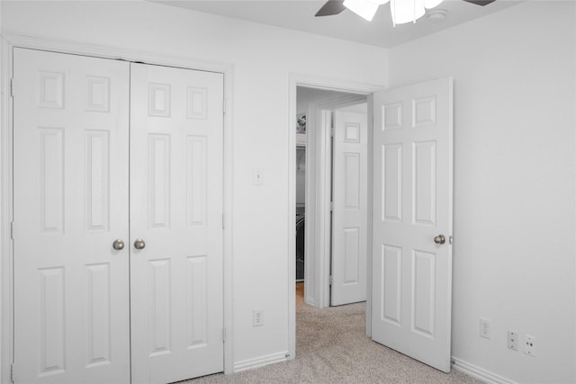 unfurnished bedroom with ceiling fan, light carpet, and a closet