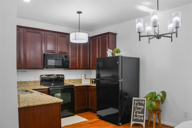 kitchen featuring light stone counters, black appliances, pendant lighting, a chandelier, and light wood-type flooring