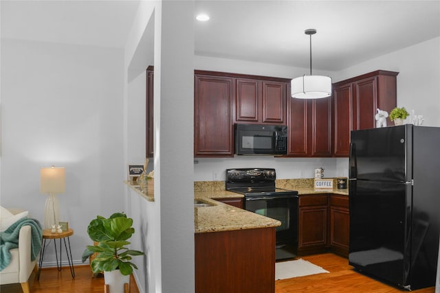 kitchen with light hardwood / wood-style floors, pendant lighting, light stone countertops, and black appliances