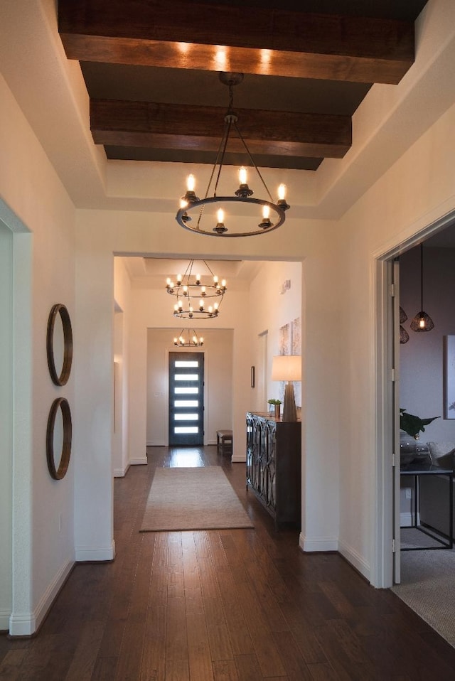 foyer entrance featuring beamed ceiling, dark wood-type flooring, and a notable chandelier