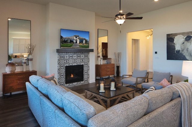 living room with ceiling fan, dark wood-type flooring, and a tiled fireplace