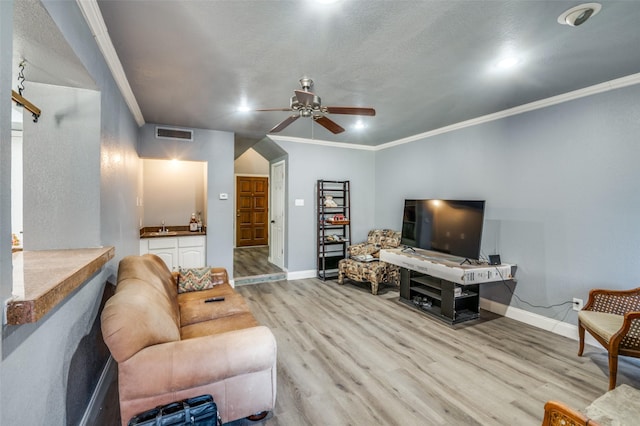 living room featuring light wood-type flooring, ornamental molding, sink, and ceiling fan