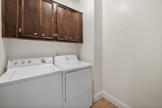 laundry area featuring cabinets, washing machine and dryer, and light tile patterned floors