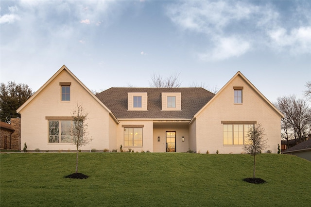 view of front facade featuring roof with shingles, brick siding, and a front lawn