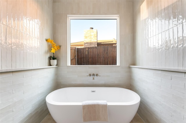 full bathroom with a freestanding tub and tile walls