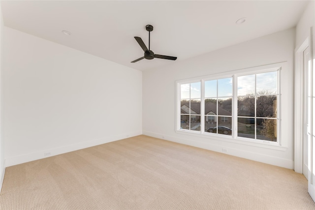 unfurnished room with baseboards, a ceiling fan, and light colored carpet