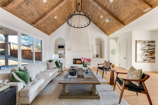 living room with wooden ceiling, a large fireplace, beamed ceiling, and an inviting chandelier