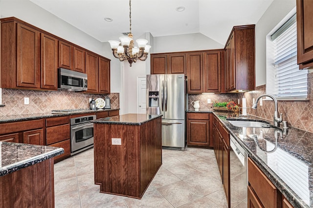 kitchen with backsplash, stainless steel appliances, dark stone countertops, a center island, and sink