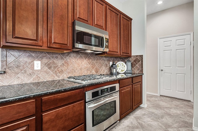 kitchen with light tile patterned floors, dark stone countertops, stainless steel appliances, and tasteful backsplash