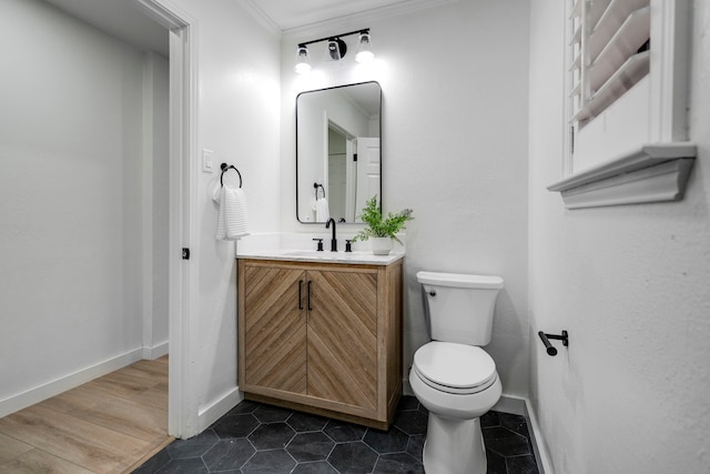 bathroom with crown molding, toilet, vanity, tile patterned flooring, and baseboards