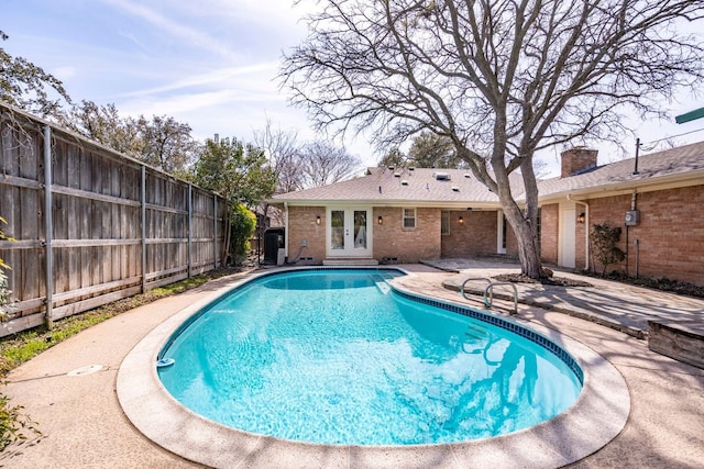 view of swimming pool with a fenced backyard, a patio, a fenced in pool, and french doors