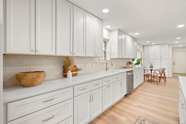 kitchen featuring white cabinets, a sink, and light wood finished floors