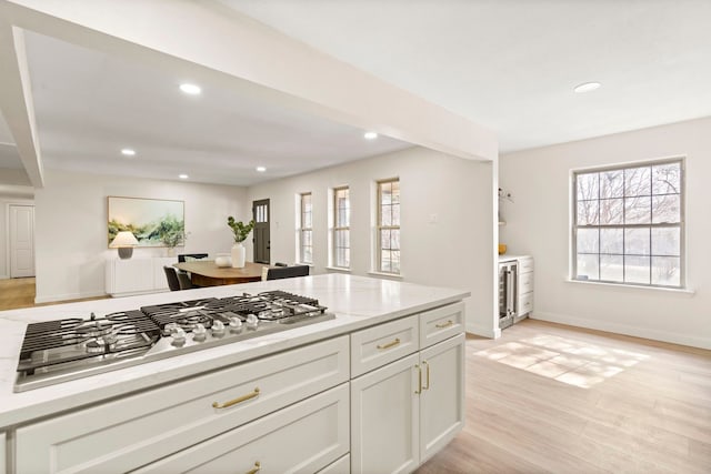 kitchen featuring white cabinets, light stone countertops, light wood-type flooring, stainless steel gas stovetop, and recessed lighting