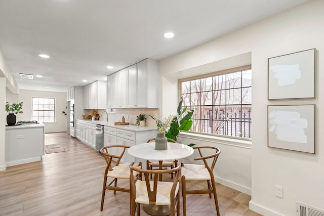 dining room with light wood finished floors, baseboards, visible vents, and recessed lighting