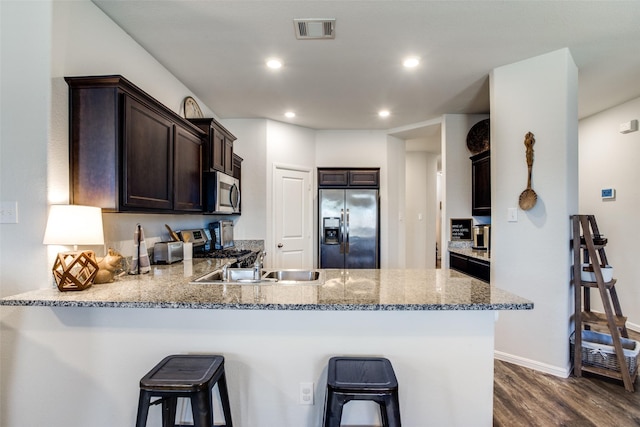 kitchen featuring stainless steel appliances, a breakfast bar area, dark hardwood / wood-style floors, and kitchen peninsula