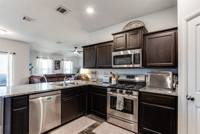 kitchen featuring kitchen peninsula, stainless steel appliances, dark brown cabinetry, sink, and ceiling fan