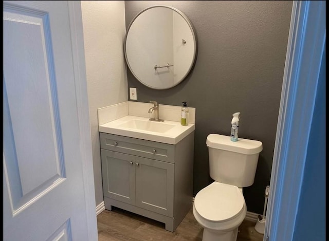 bathroom featuring hardwood / wood-style flooring, toilet, and vanity