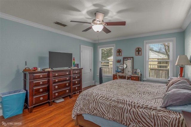 bedroom featuring visible vents, multiple windows, crown molding, and wood finished floors