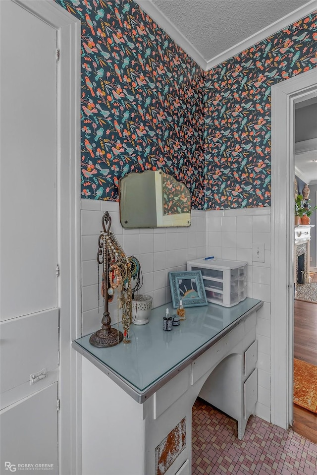 home office featuring wallpapered walls, a textured ceiling, tile walls, and wainscoting