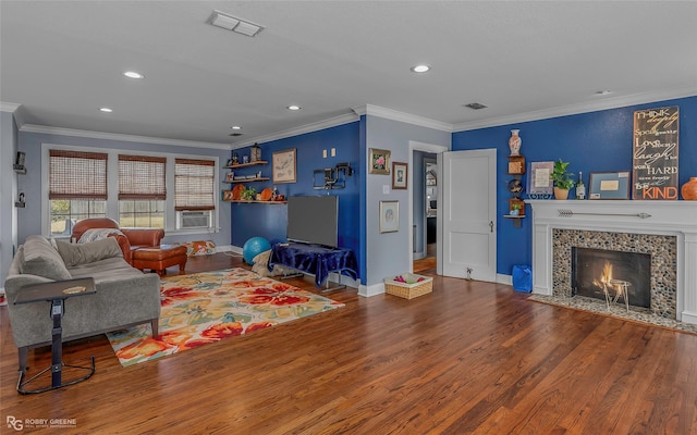 living area featuring visible vents, crown molding, baseboards, a fireplace, and wood finished floors