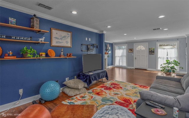 living room with visible vents, wood finished floors, and ornamental molding