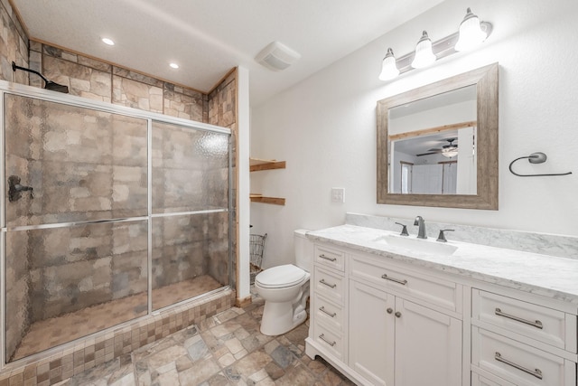 bathroom featuring toilet, stone finish flooring, a shower stall, and vanity