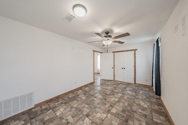 unfurnished bedroom featuring stone finish floor, a closet, visible vents, and baseboards