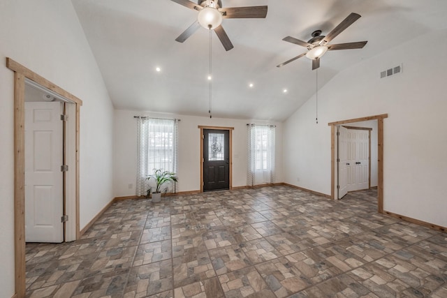 foyer entrance featuring stone finish flooring, high vaulted ceiling, visible vents, and baseboards