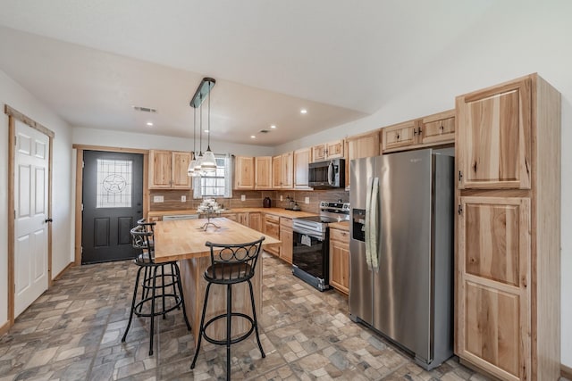 kitchen featuring a center island, stainless steel appliances, visible vents, hanging light fixtures, and light brown cabinetry