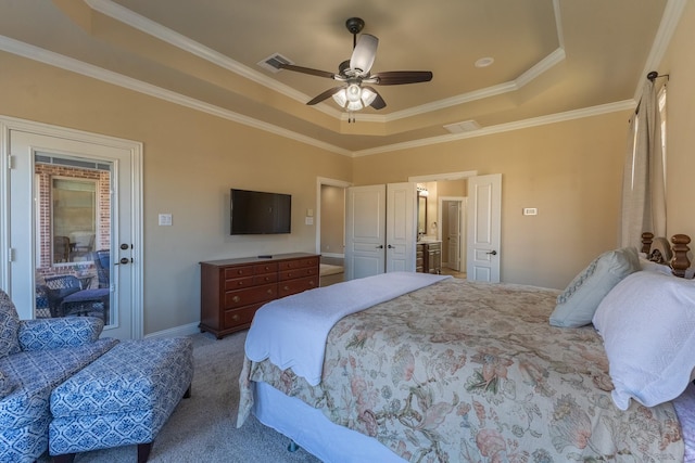 carpeted bedroom featuring a tray ceiling, ornamental molding, ceiling fan, and ensuite bath