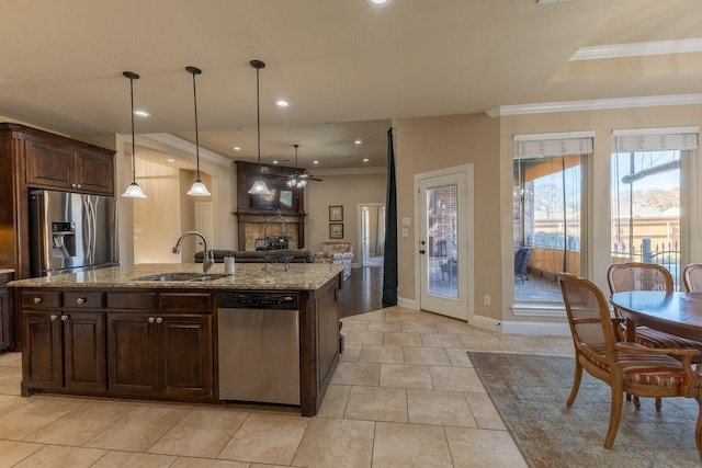 kitchen with appliances with stainless steel finishes, dark brown cabinets, an island with sink, decorative light fixtures, and sink