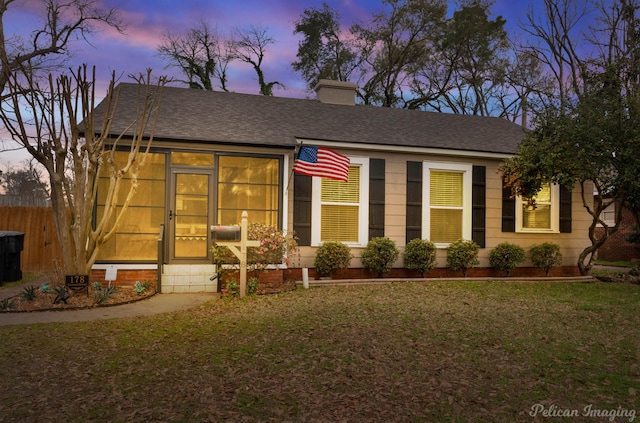 view of front of property featuring a chimney, fence, a front yard, and a shingled roof