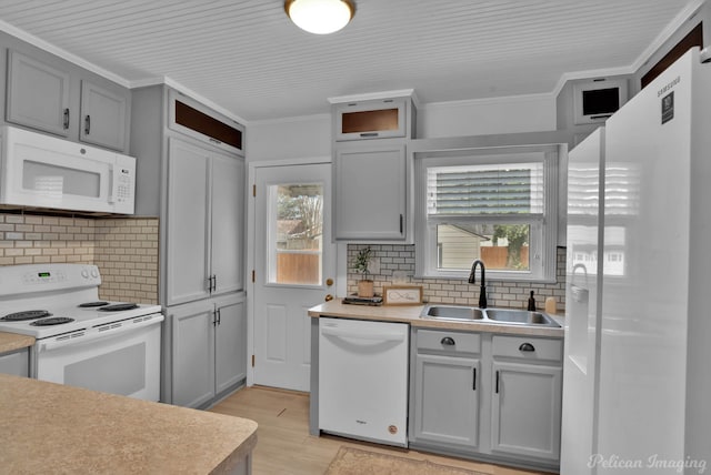 kitchen with white appliances, ornamental molding, light wood-type flooring, and a sink