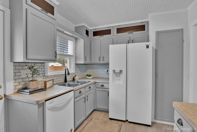 kitchen with a sink, white appliances, ornamental molding, and light countertops