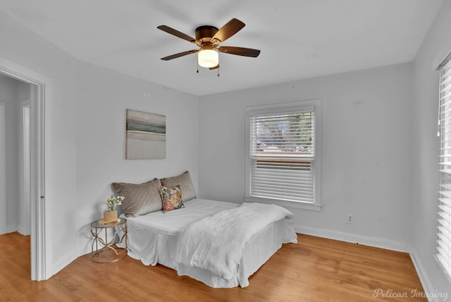 bedroom with a ceiling fan, wood finished floors, and baseboards