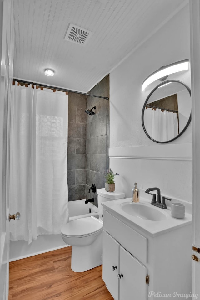 full bathroom featuring vanity, wood finished floors, visible vents, shower / bath combo with shower curtain, and toilet