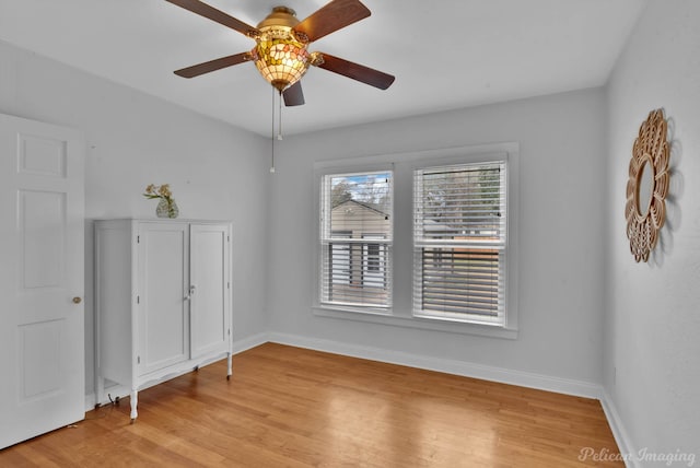 spare room featuring baseboards, light wood-style floors, and ceiling fan