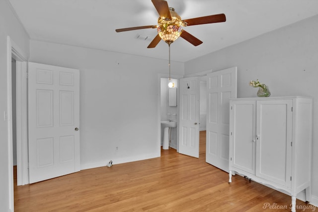 unfurnished bedroom with baseboards, ensuite bath, a ceiling fan, and light wood finished floors