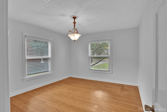 unfurnished room with baseboards, a textured ceiling, and light wood finished floors