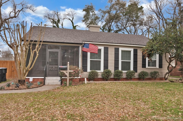 view of front of property featuring a front yard, fence, a sunroom, a shingled roof, and a chimney