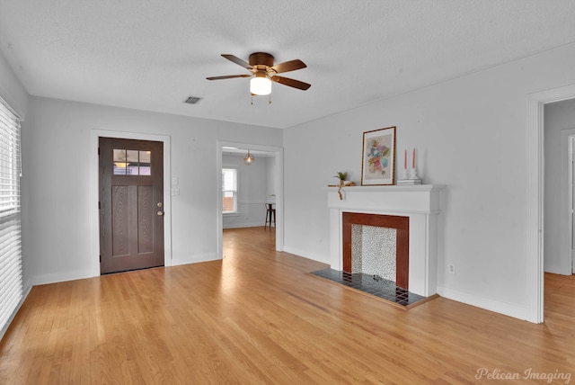 unfurnished living room featuring visible vents, a fireplace, a textured ceiling, and wood finished floors